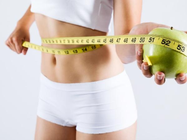 Weight loss. Green measuring tape on woman body - Mile High Spine